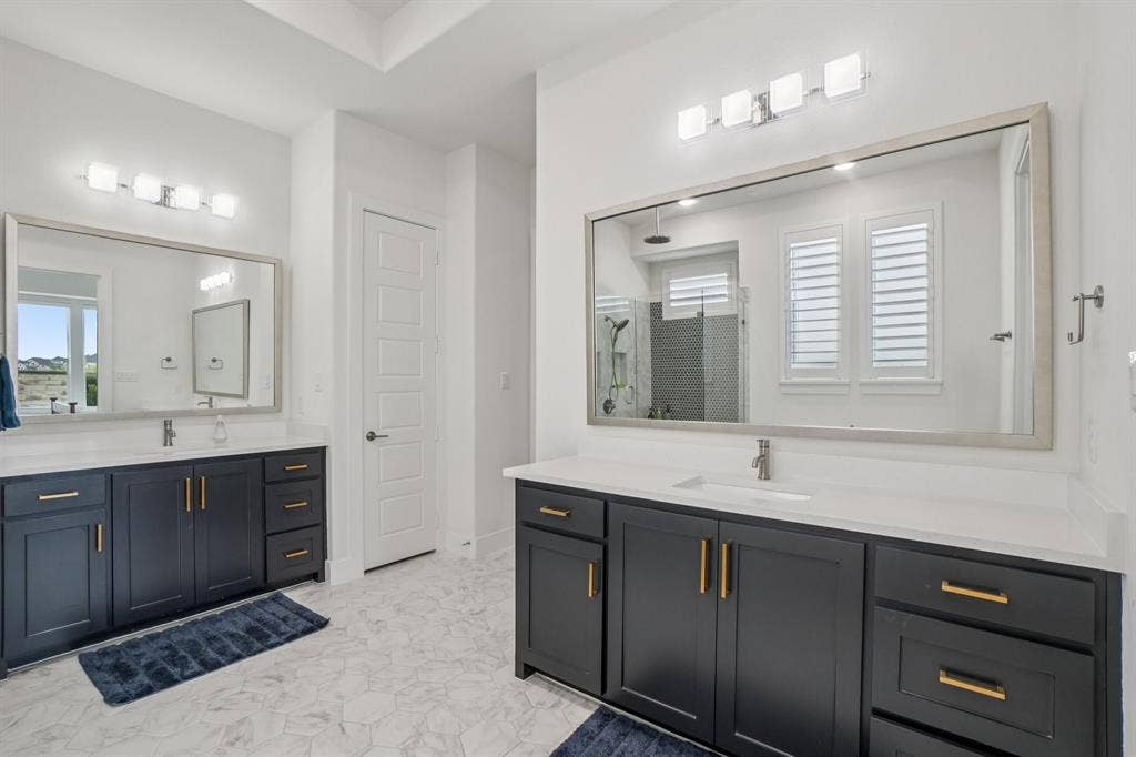 3960 Medio Creek Drive, Prosper, TX 75078 Spacious bathroom featuring dual vanities with dark cabinetry, white countertops, and brushed brass hardware