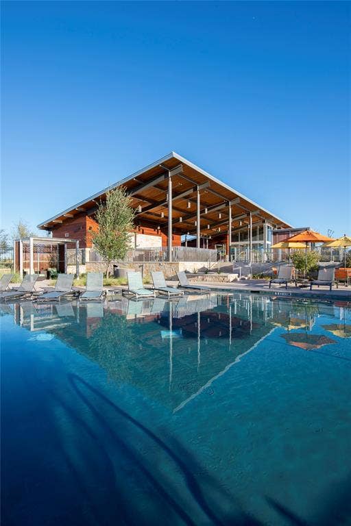 3960 Medio Creek Drive, Prosper, TX 75078 Expansive swimming pool with integrated lounge seating, reflecting a contemporary open-air pavilion