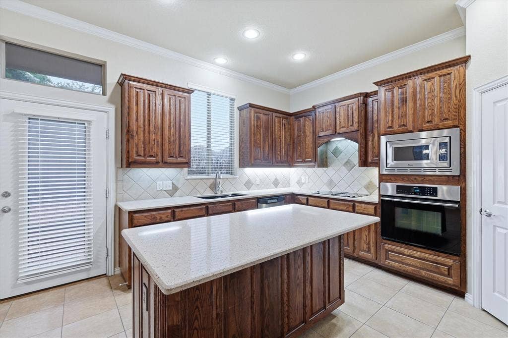 1905 Fountain Meadows Drive, Euless, TX 76039 Kitchen featuring rich wood cabinetry, light-toned Corian countertops, tile flooring, stainless steel built-in appliances (mostly Jenn-Air brand), and large walk-in pantry.