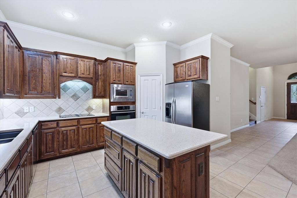 1905 Fountain Meadows Drive, Euless, TX 76039 Island features ample storage and bar seating. Electric Jenn-Air cooktop has downdraft exhaust. Under the counter lights round out this perfect space.