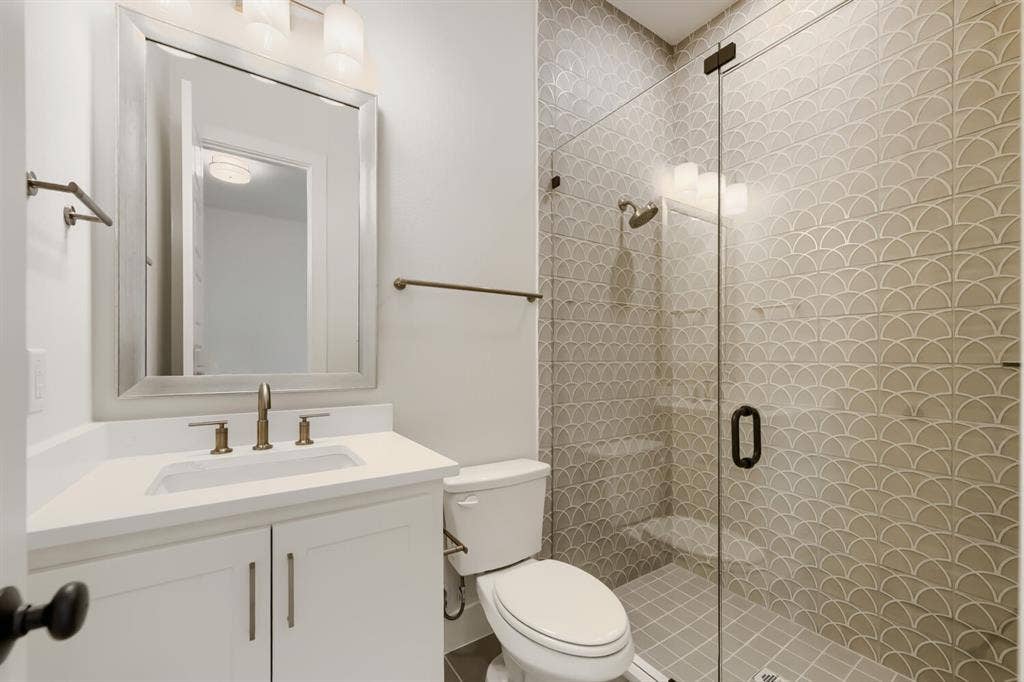 1317 Naples Court, Keller, TX 76248 Bathroom featuring a glass-enclosed shower with decorative scallop tile, white vanity with integrated sink, and bronze-finish fixtures