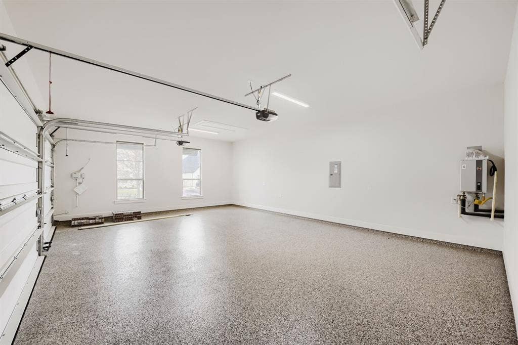 1317 Naples Court, Keller, TX 76248 Large garage space featuring a speckled epoxy floor, two windows with blinds, and white walls