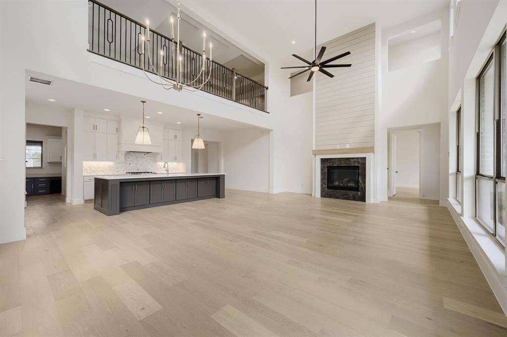 1317 Naples Court, Keller, TX 76248 Two-story interior with wood-finish flooring, a kitchen island with seating, pendant lighting, and a fireplace with shiplap-paneled surround