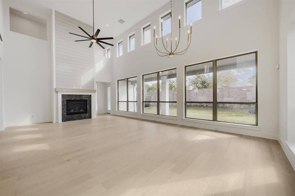 1317 Naples Court, Keller, TX 76248 Expansive living space featuring wood-finish flooring, a fireplace with a dark stone surround and shiplap accent wall, and multiple large windows