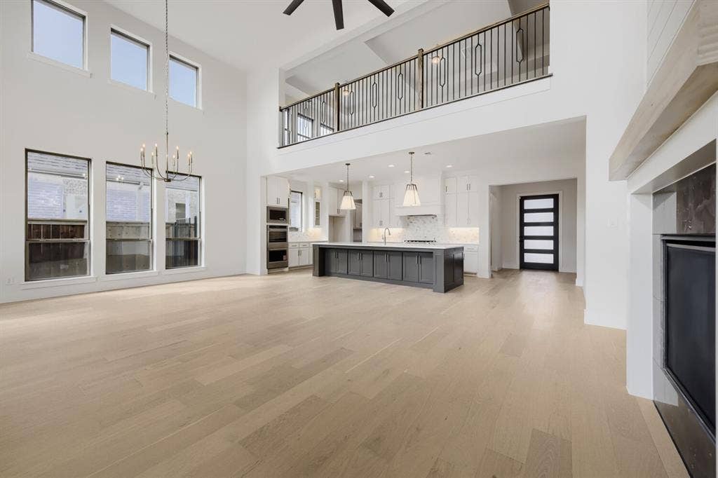 1317 Naples Court, Keller, TX 76248 Expansive open-concept space featuring high ceilings, wood-finish flooring, and a contemporary kitchen with a dark-toned island
