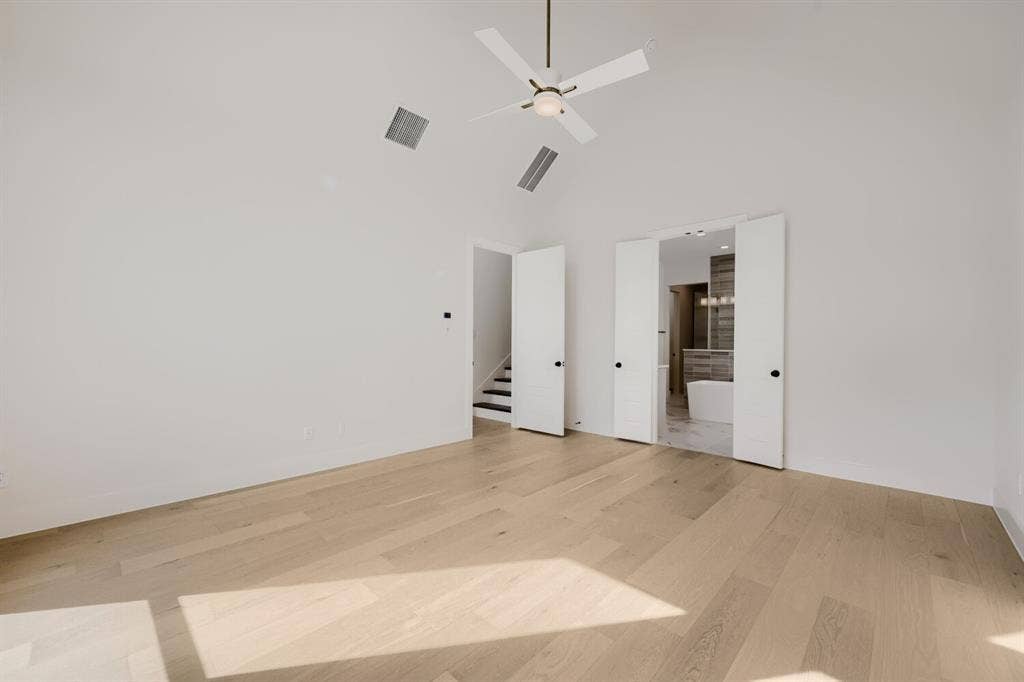 1317 Naples Court, Keller, TX 76248 Vaulted ceiling with a ceiling fan, light wood-finish flooring, and white bifold doors revealing a freestanding bathtub