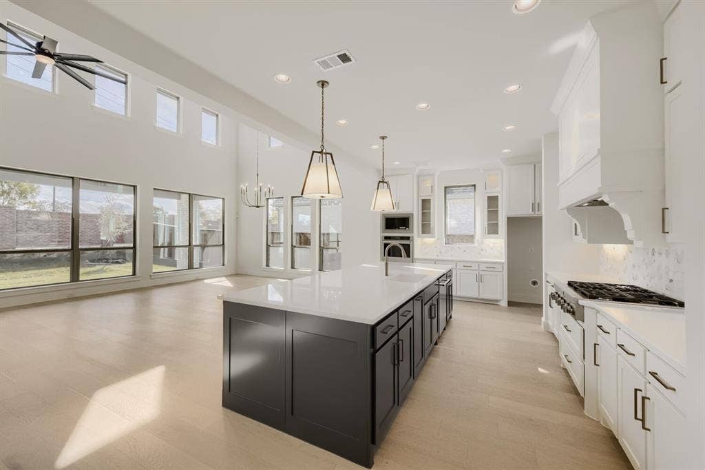 1317 Naples Court, Keller, TX 76248 Spacious open-concept layout featuring high ceilings, wood-finish flooring, a contemporary kitchen island with a built-in sink, and extensive recessed lighting