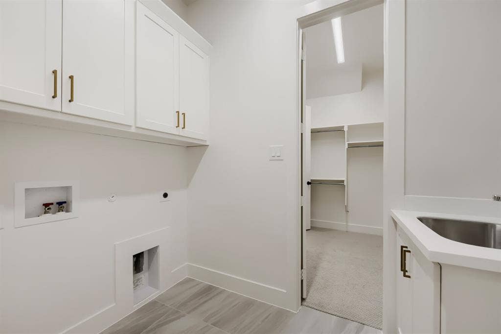 1317 Naples Court, Keller, TX 76248 White shaker cabinetry with gold-tone hardware, utility sink with white countertop, gray wood-finish tile flooring, and dedicated laundry hookups