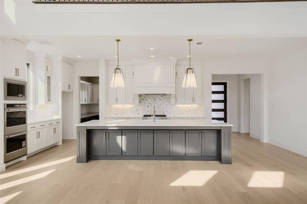 1317 Naples Court, Keller, TX 76248 Kitchen featuring a large island with gray cabinetry, white perimeter cabinetry, stainless steel double ovens, and wood-finish flooring