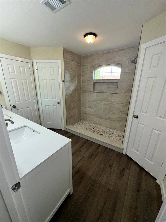 6620 Moss Lane, Watauga, TX 76148 Walk-in shower featuring light-toned tile surround, built-in shelving, and a pebble-stone floor