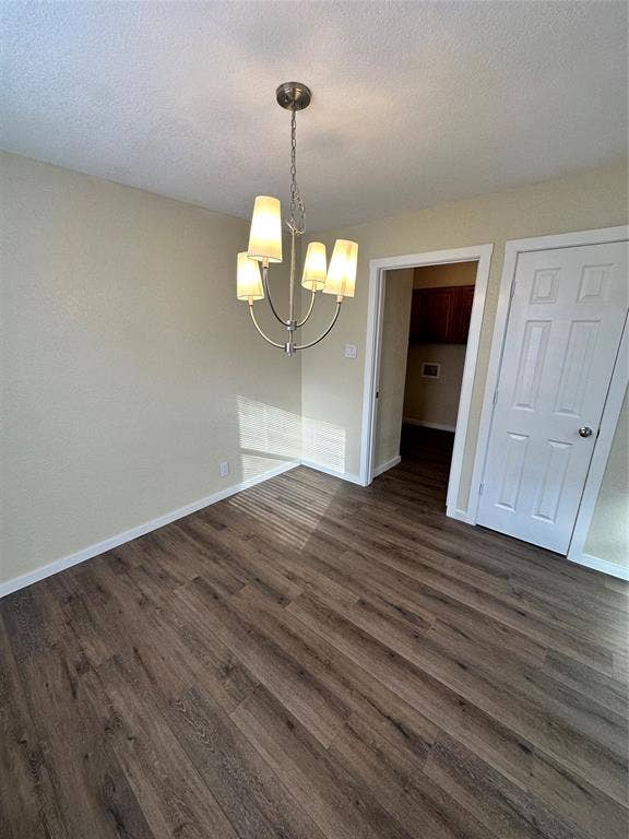 6620 Moss Lane, Watauga, TX 76148 Spacious room featuring wood-finish flooring, a contemporary brushed nickel chandelier with four shaded lights, light-colored walls, and white baseboards