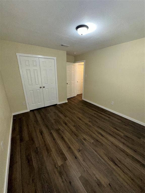 6620 Moss Lane, Watauga, TX 76148 Expansive room featuring wood-finish flooring, two-panel bifold closet doors, light-toned wall paint, white baseboards, and a semi-flush mount ceiling light fixture