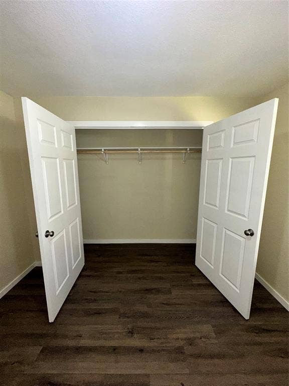 6620 Moss Lane, Watauga, TX 76148 Spacious closet featuring bi-fold panel doors, wood-finish flooring, and a built-in clothing rod with shelving