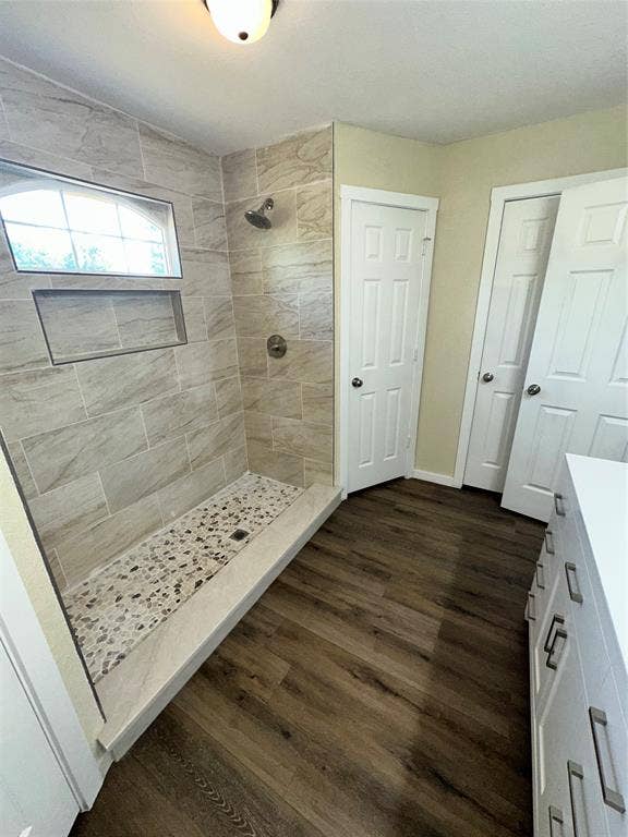 6620 Moss Lane, Watauga, TX 76148 Walk-in shower with natural stone-look wall tiles, pebble-style flooring, and a built-in recessed niche