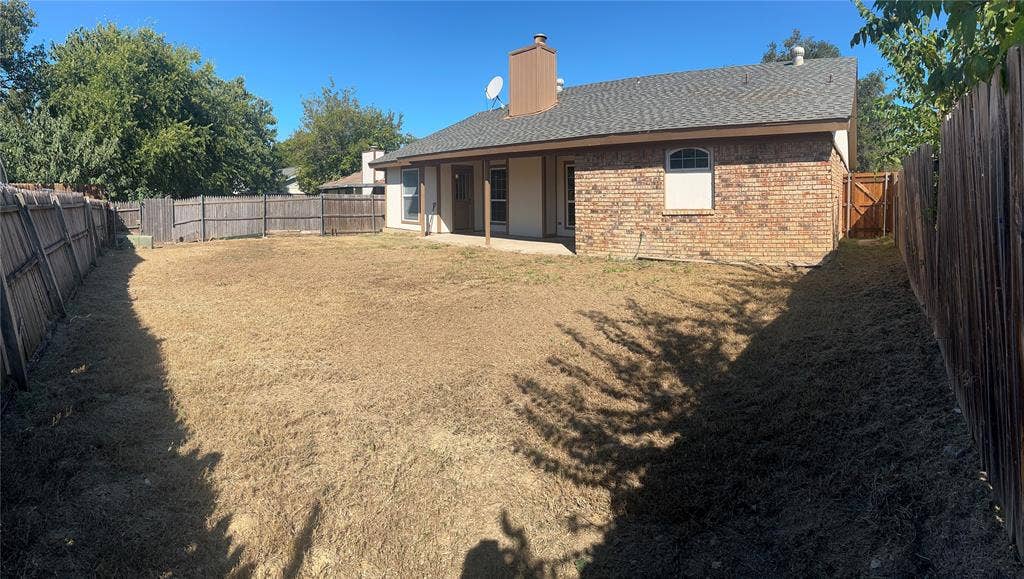 6620 Moss Lane, Watauga, TX 76148 Expansive fenced backyard with a brick exterior, a covered patio, and a side access gate