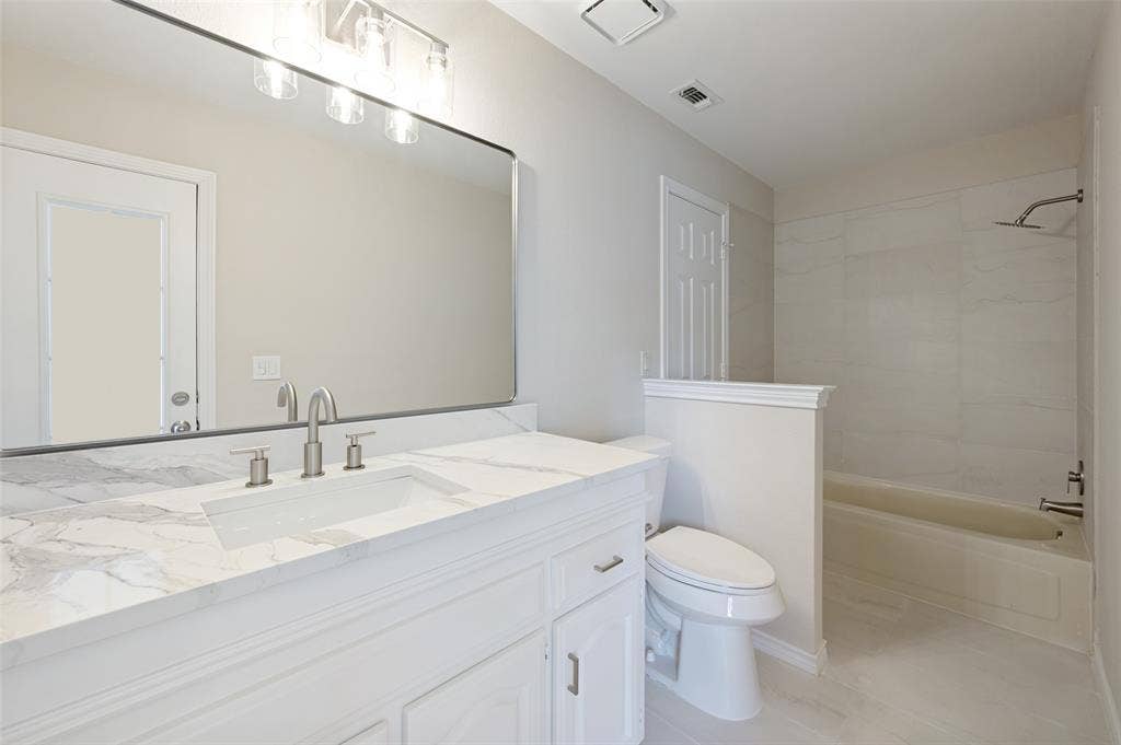 4420 Barwyn Lane, Plano, TX 75093 Bathroom featuring a white vanity with a marble-patterned countertop, an integrated rectangular sink, and brushed nickel fixtures