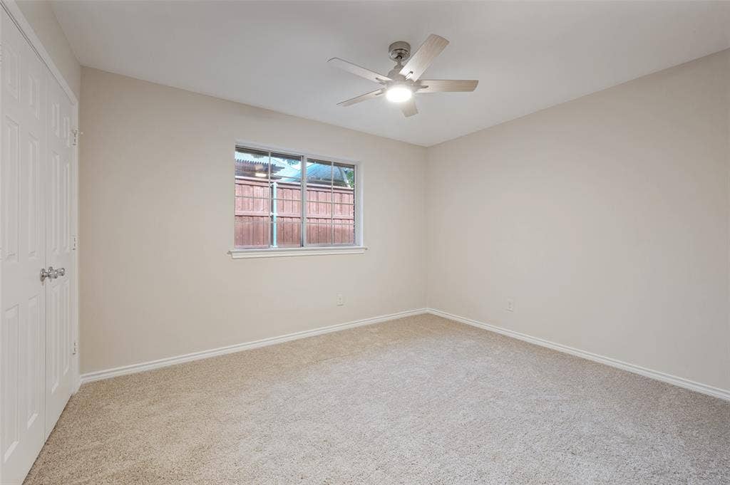 4420 Barwyn Lane, Plano, TX 75093 Carpeted room featuring a ceiling fan with integrated lighting, a window with a white frame, and a paneled bifold closet door