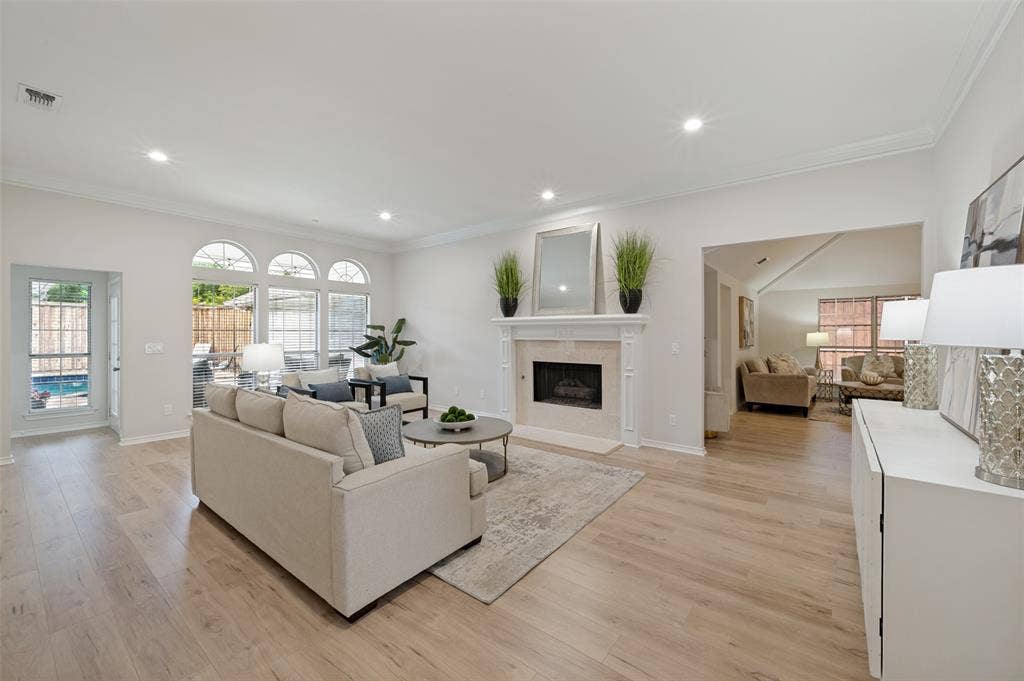 4420 Barwyn Lane, Plano, TX 75093 Spacious living area featuring light wood-finish flooring, a stone-surround fireplace with a white mantel, recessed lighting, and crown molding