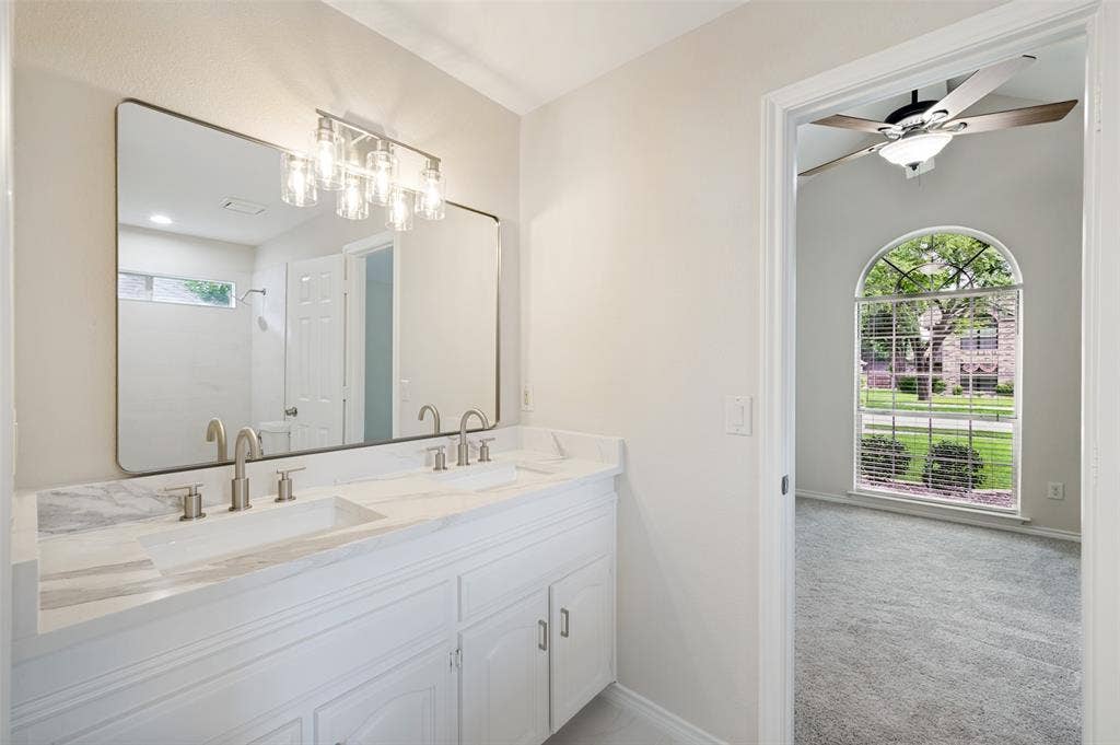 4420 Barwyn Lane, Plano, TX 75093 Double vanity with integrated sinks and brushed nickel fixtures, complemented by a rectangular mirror with a metal frame and a five-light vanity fixture