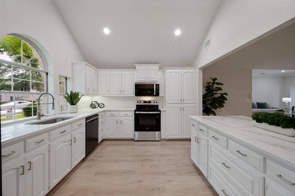 4420 Barwyn Lane, Plano, TX 75093 Kitchen featuring high vaulted ceilings, white cabinetry with silver hardware, a large arched window, and wood-finish flooring