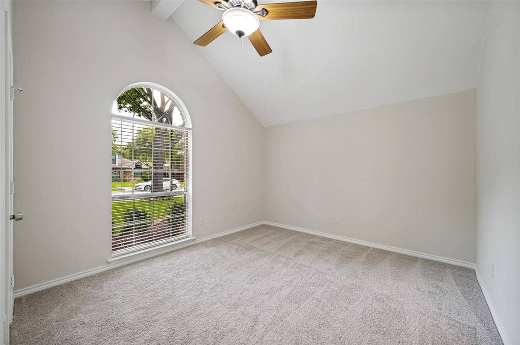 4420 Barwyn Lane, Plano, TX 75093 Arched window with street-facing views, vaulted ceiling, neutral wall paint, ceiling fan with light fixture, and gray carpet flooring