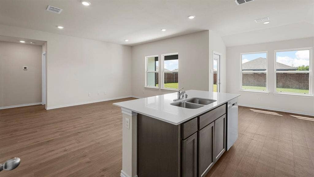 Kitchen island featuring a double-basin stainless steel sink, chrome faucet, and integrated dishwasher