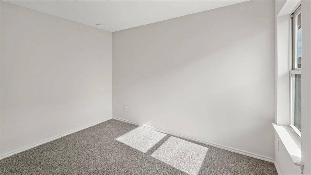 1969 Freeman Street, Tyler, TX 75702 Room featuring neutral gray walls, gray carpeting, white baseboards, and a single-pane window with a white frame