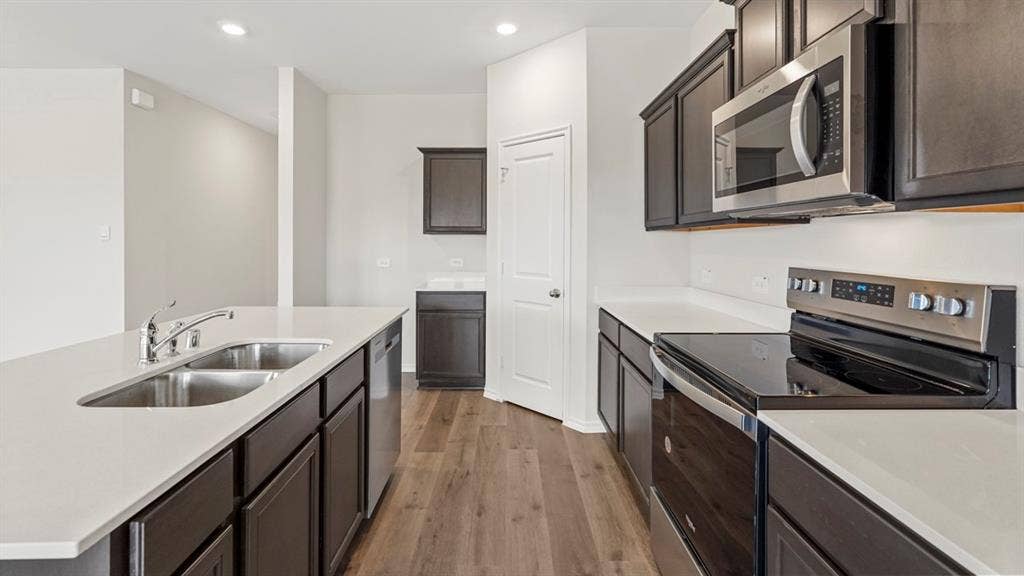 1969 Freeman Street, Tyler, TX 75702 Modern kitchen featuring dark wood-finish cabinetry, light countertops, a stainless steel double basin sink, and wood-finish flooring