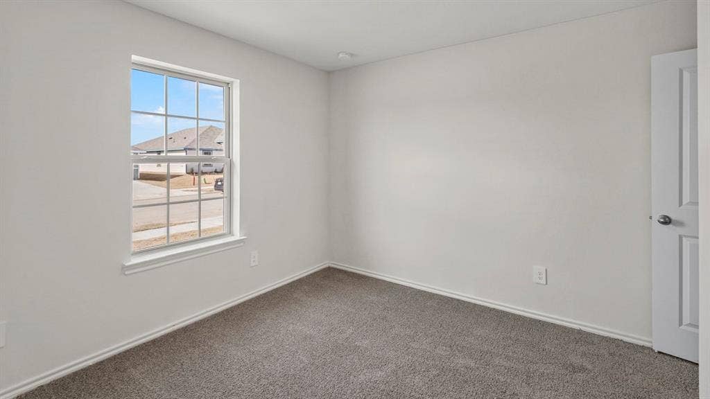 1969 Freeman Street, Tyler, TX 75702 Bright room featuring a grid-pattern window, neutral wall paint, gray carpet flooring, white baseboards, and a white interior door