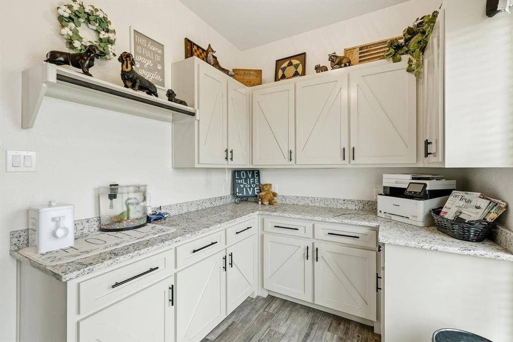 L-shaped counter space with granite-style countertops and white cabinetry featuring barn-door style accents