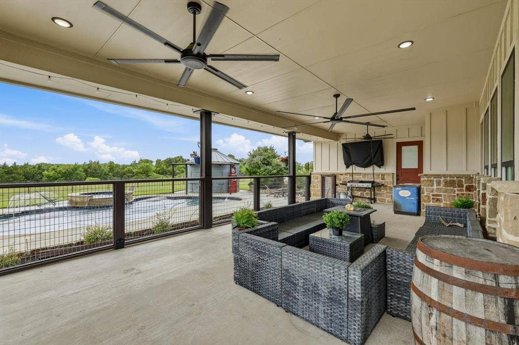 Expansive covered patio featuring a concrete surface, multiple ceiling fans, recessed lighting, and a metal railing system