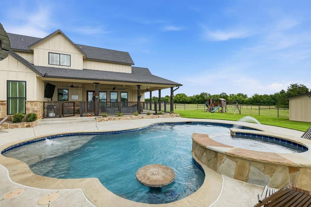Resort-style backyard featuring a freeform swimming pool with integrated spa and water features
