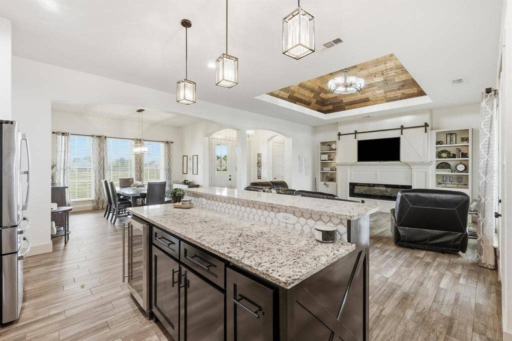Kitchen island featuring a granite countertop, hexagonal tile backsplash, and dark wood cabinetry