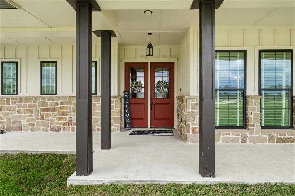 Covered front entry featuring robust dark pillars and a concrete porch