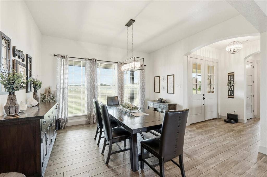 Open-concept dining area featuring wood-finish tile flooring and an arched entryway