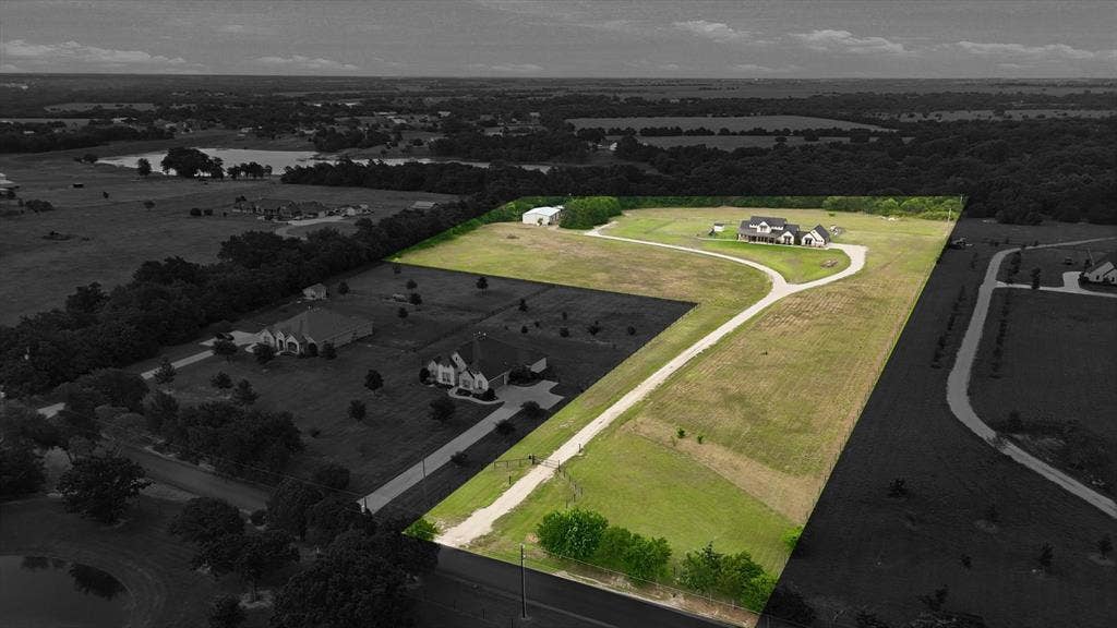 Expansive rural property featuring a long gravel driveway, a large residence, and a detached outbuilding