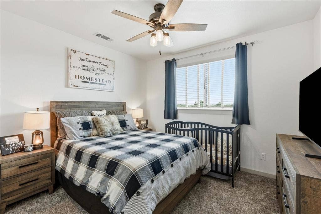 Carpeted room featuring a ceiling fan with integrated lighting, a window with blinds, and light-toned walls