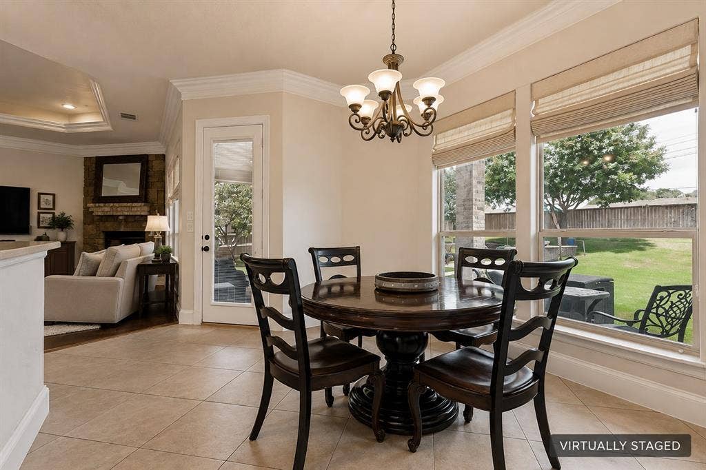 Tile flooring, crown molding, decorative chandelier, large windows with garden views, and a glass-paneled exterior door