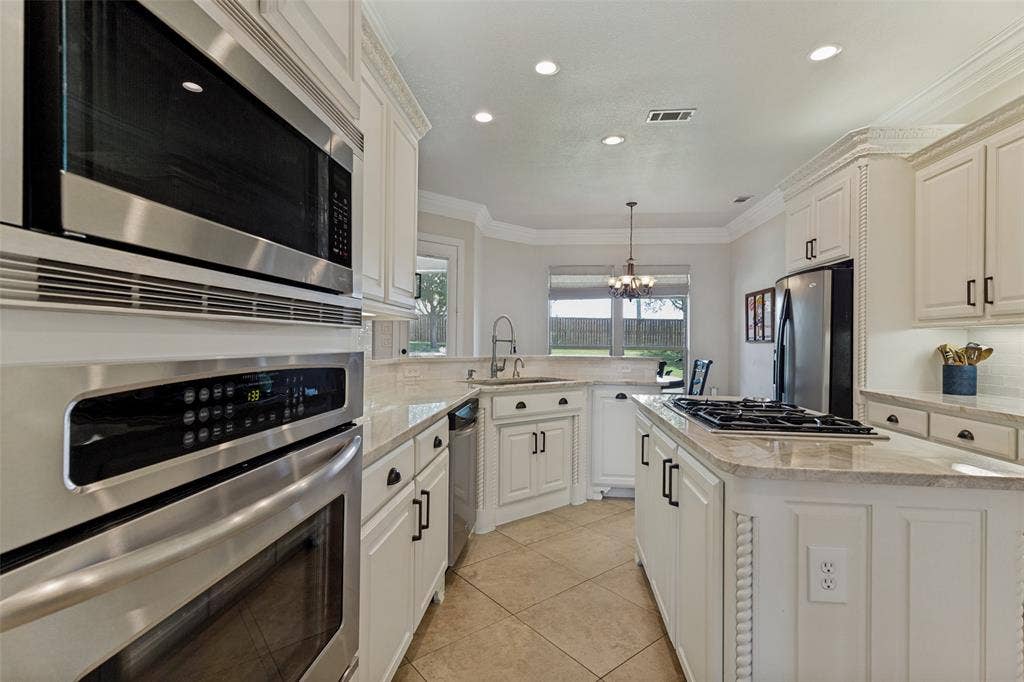 Modern kitchen featuring white cabinetry, stainless steel appliances, recessed lighting, and a kitchen island with a gas cooktop