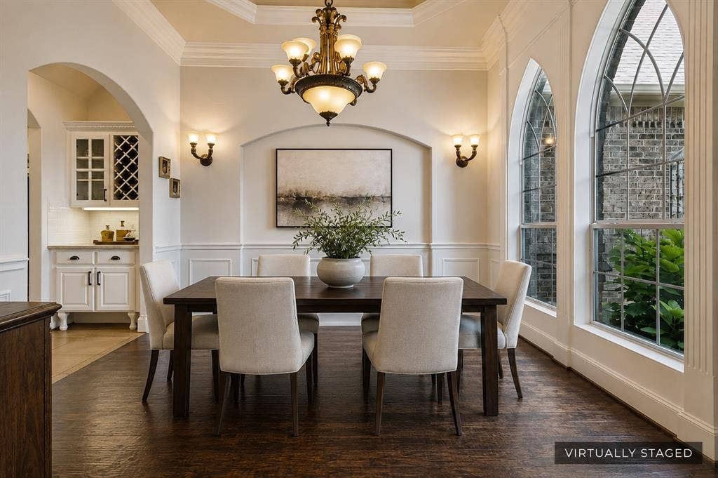 Hardwood-finish flooring throughout, ornate chandelier, decorative wall sconces, arched windows, and built-in cabinetry with wine storage