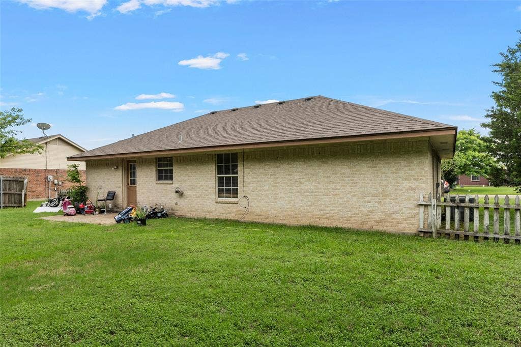 1307 Luanne, Bellmead, TX 76705 Expansive green lawn surrounds a brick exterior home with a partial picket fence