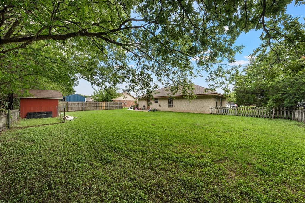 1307 Luanne, Bellmead, TX 76705 Spacious backyard featuring a large lawn, mature trees, and a wooden privacy fence