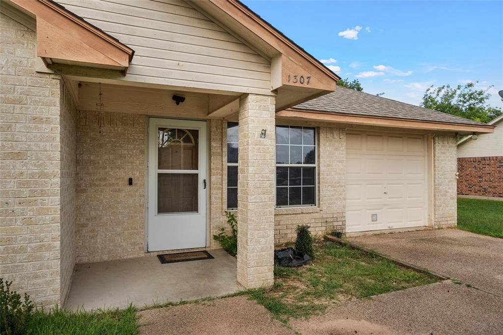1307 Luanne, Bellmead, TX 76705 Cream brick exterior featuring a covered entry, single-car garage, and shuttered window