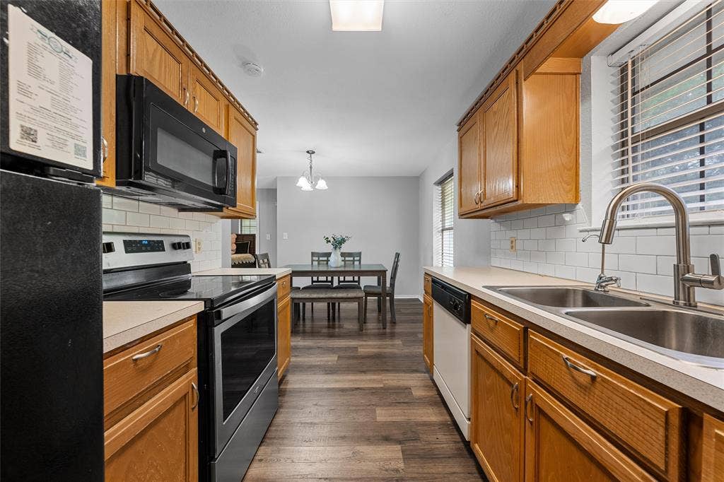 1307 Luanne, Bellmead, TX 76705 Galley-style kitchen featuring wood-finish cabinetry, white subway tile backsplash, and light-toned countertops