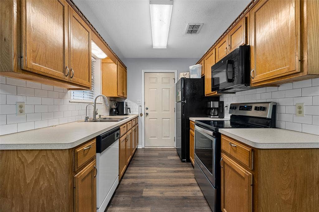 1307 Luanne, Bellmead, TX 76705 Galley kitchen featuring wood cabinetry, white subway tile backsplash, light-toned countertops, and wood-finish flooring