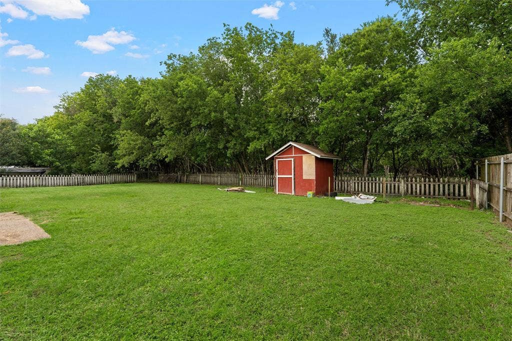 1307 Luanne, Bellmead, TX 76705 Expansive backyard with a manicured green lawn, bordered by a picket fence and mature trees