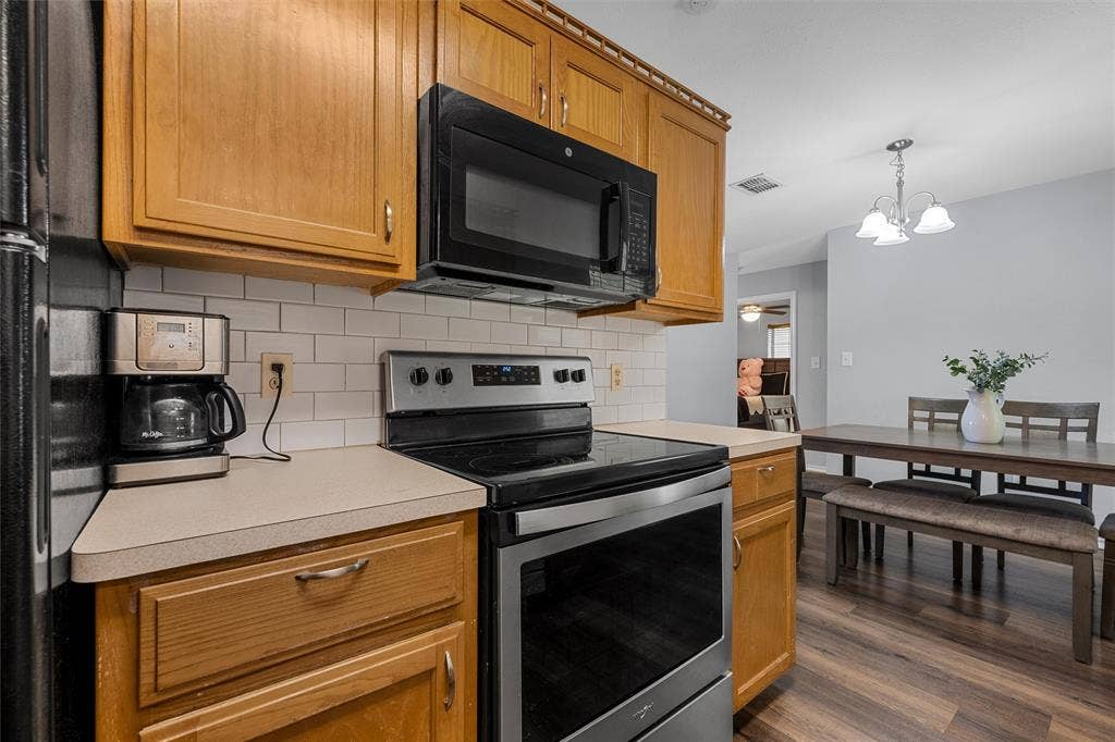 1307 Luanne, Bellmead, TX 76705 Kitchen featuring wood cabinetry, light-toned countertops, a white subway tile backsplash, and stainless steel appliances including a range and over-the-range microwave