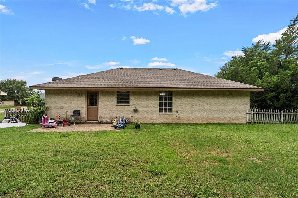 1307 Luanne, Bellmead, TX 76705 Expansive backyard with a concrete patio, light-colored brick exterior, and a brown shingle roof