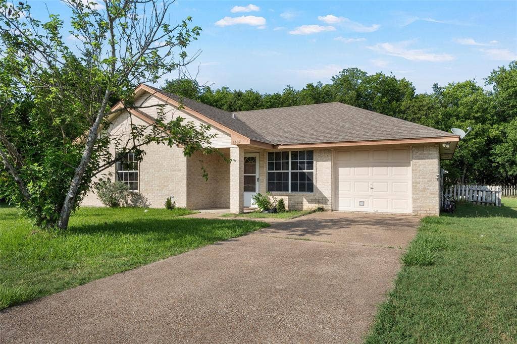 1307 Luanne, Bellmead, TX 76705 Single-story residence featuring a light brick exterior, a single-car garage, and a concrete driveway