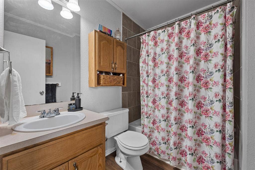 1307 Luanne, Bellmead, TX 76705 Bathroom featuring a wood-finish vanity with an integrated sink, a wall-mounted mirror, and overhead lighting